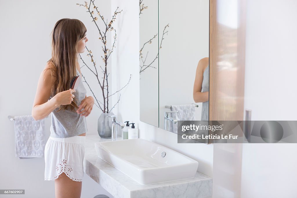 Woman combing hair in a bathroom