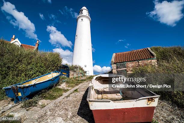 rowboats on the shore at the base of st. marys lighthouse on st. marys island - st marys island stock pictures, royalty-free photos & images