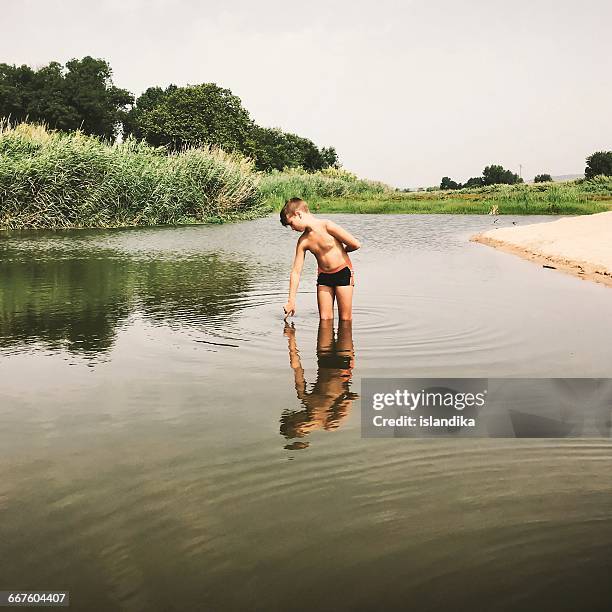 boy standing in river - boy swimming stock pictures, royalty-free photos & images