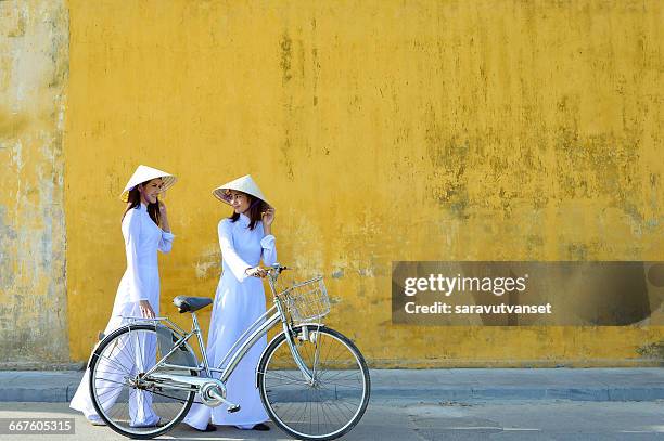 two women in traditional clothing standing in street talking, hoi an, vietnam - hoi an stockfoto's en -beelden