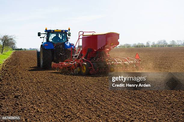 farm tractor and seed drill sowing ploughed field in spring - sow stock pictures, royalty-free photos & images