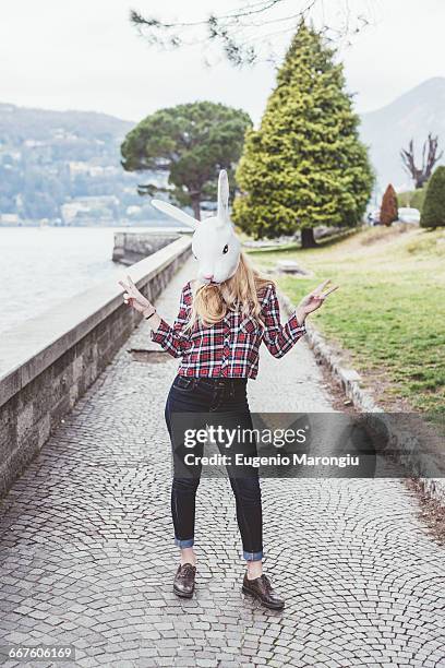 portrait of woman wearing rabbit mask making peace sign, lake como, italy - rabbit mask fotografías e imágenes de stock