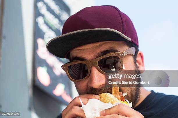 male customer eating hamburger from fast food van - sigrid gombert stock-fotos und bilder