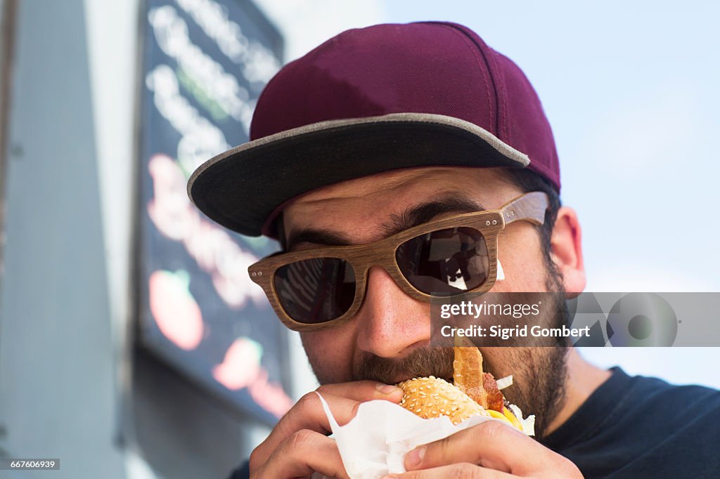 Male customer eating hamburger from fast food van