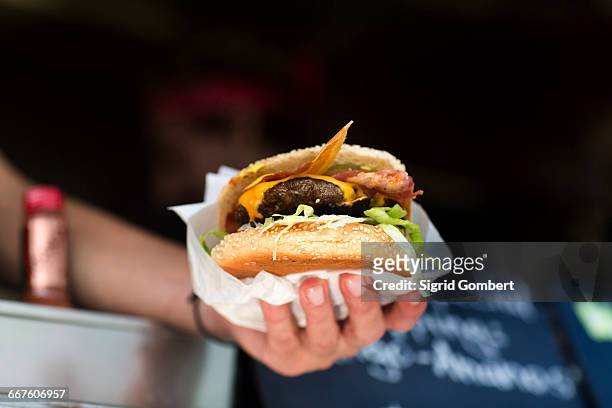 mans hand serving hamburger from fast food van - hand holding burger stock pictures, royalty-free photos & images