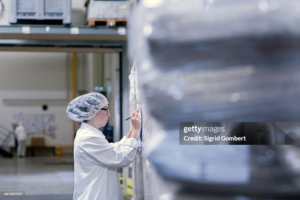 Factory worker writing on paperwork