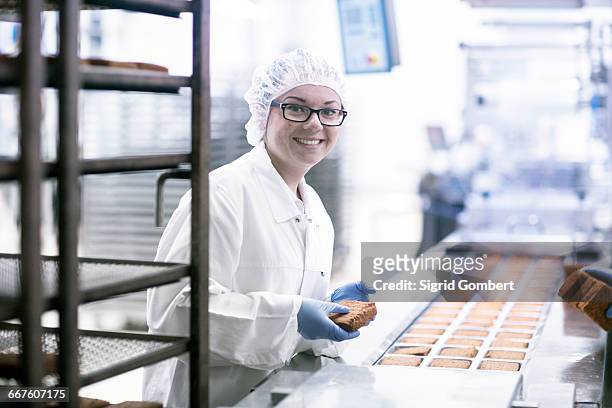 factory worker on food production line looking at camera smiling - hair net stock pictures, royalty-free photos & images