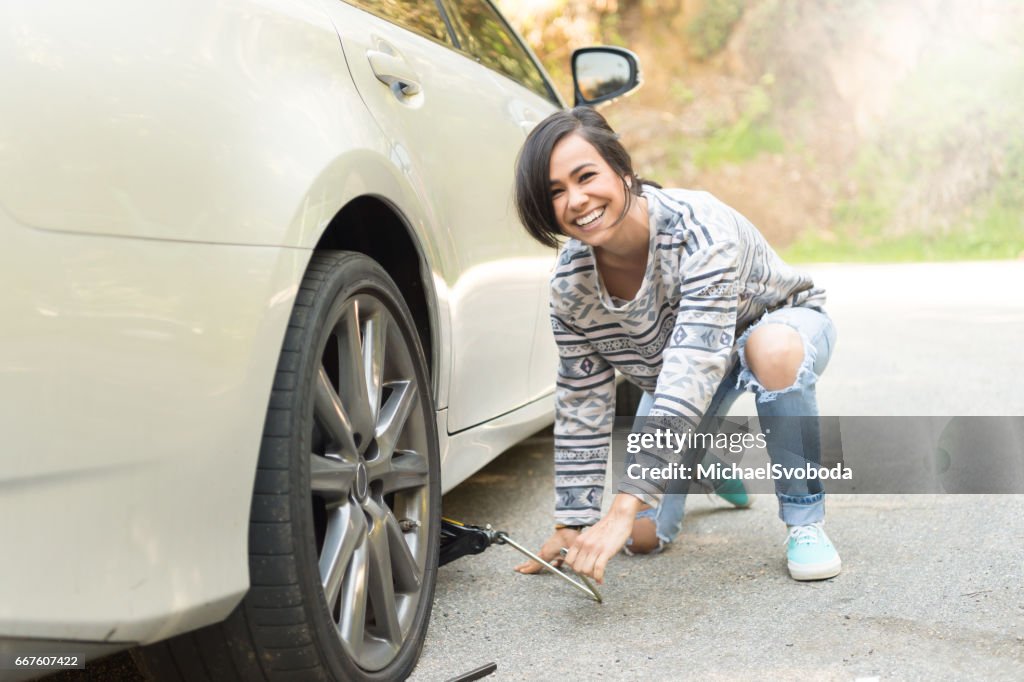 Young Women Changing A Flat Tire