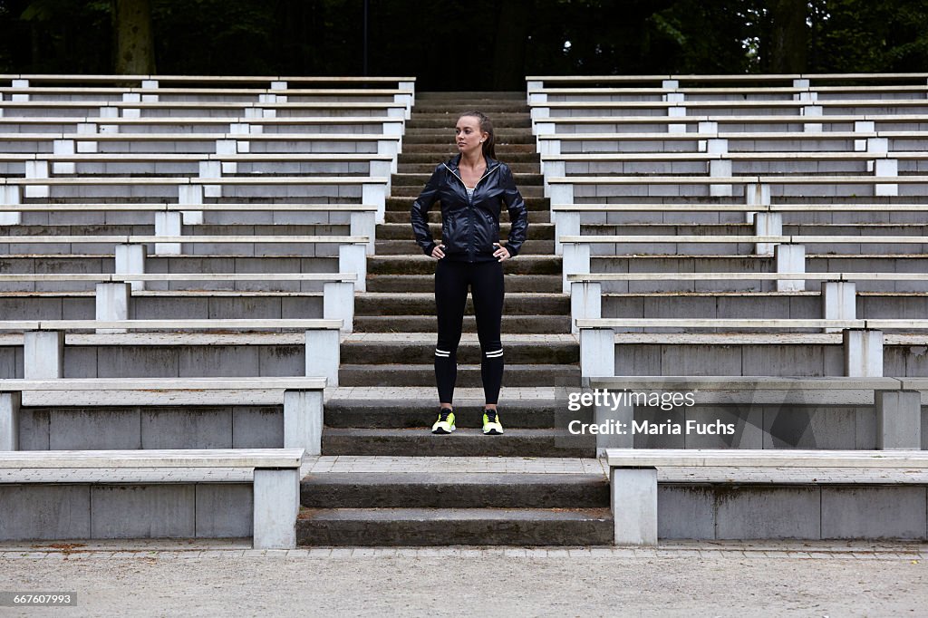 Young woman training, preparing to run on stadium stairway