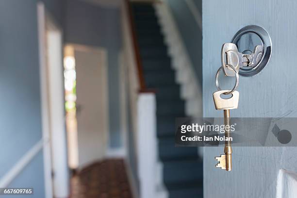 front door of house with key in lock - schlüssel stock-fotos und bilder