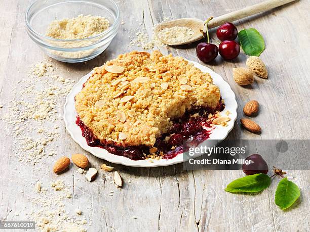 sour cherry and almond crumble pudding, almonds, cherries, white washed rustic wooden table - almond joy stock pictures, royalty-free photos & images