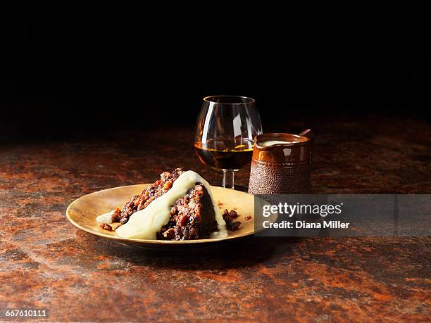 vanilla and armagnac sauce poured over christmas pudding, glass of brandy and pot of sauce - cognac stockfoto's en -beelden