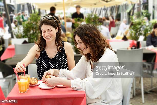 two women chatting and having breakfast at sidewalk cafe, milan, italy - milan cafe stock pictures, royalty-free photos & images