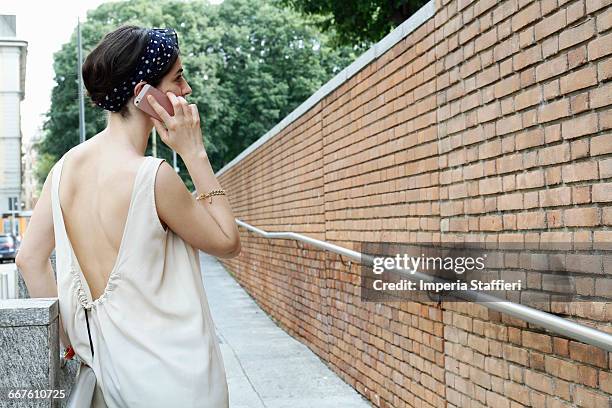 stylish woman talking on smartphone on street, milan, italy - backless stock pictures, royalty-free photos & images
