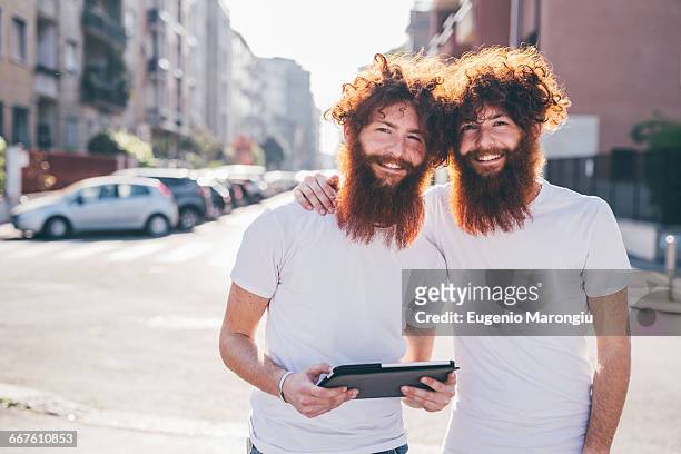 portrait of young male hipster twins with red hair and beards on city street - twin stock pictures, royalty-free photos & images