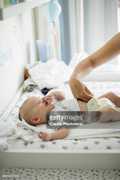 mothers hand checking looseness of baby sons diaper - adult baby boy diaper change foto e immagini stock