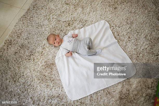 swaddling step 1. baby boy lying on blanket - babydecke stock-fotos und bilder