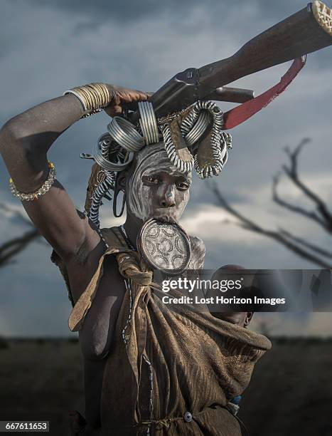 woman of the mursi tribe with kalashnikov and small child, omo valley, ethiopia - african tribal face painting 個照片及圖片檔