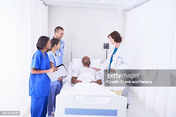 doctors and nurses surrounding patient in hospital bed - circondare foto e immagini stock