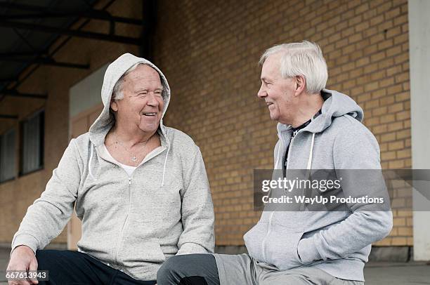 senior friends wearing sports clothes sitting together - man and his hoodie stockfoto's en -beelden