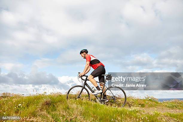 cyclist riding past meadow - 單車衫 個照片及圖片檔