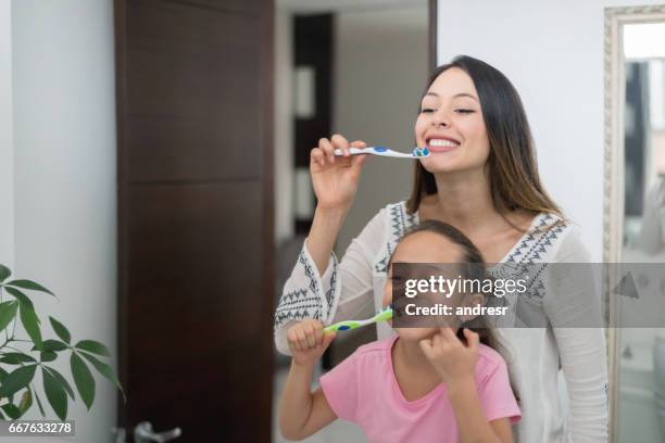 mother and daughter at home brushing their teeth - brushing teeth stock pictures, royalty-free photos & images