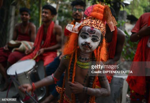 An Indian child dressed as the Hindu deity Shiva dances with others as they begs for alms in Siliguri on April 12 ahead of the 'Charak' ritual that...