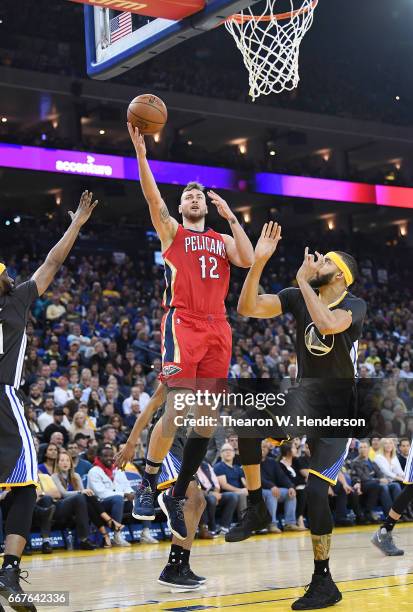 Donatas Motiejunas of the New Orleans Pelicans goes up for a layup over JaVale McGee of the Golden State Warriors during an NBA Basketball game at...