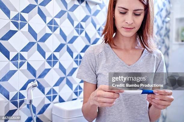 woman looking at pregnancy test - pregnancy test stock pictures, royalty-free photos & images