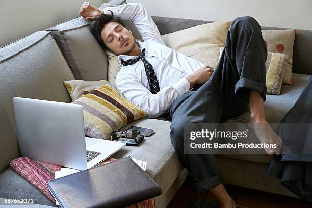 man sleeping on the couch exhausted - idle stock pictures, royalty-free photos & images