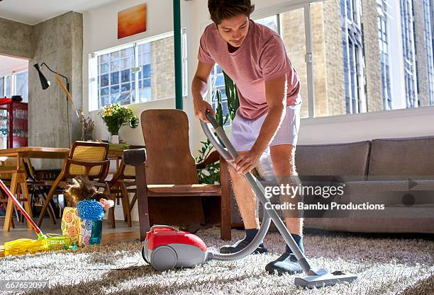 man doing housework vacuuming - aspirapolvere foto e immagini stock