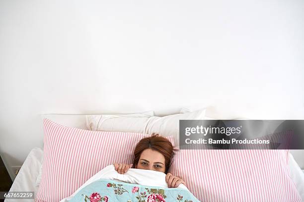 up view of a woman playing hide under the sheets - one mid adult woman only fotografías e imágenes de stock