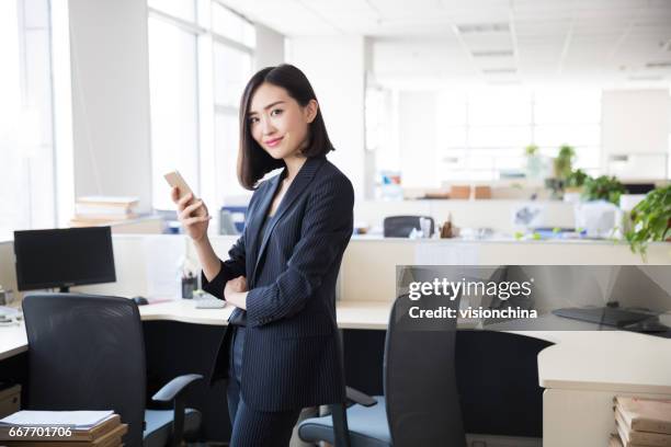 young woman wearing a black suit,using the phone in the office - asian females on a phone imagens e fotografias de stock