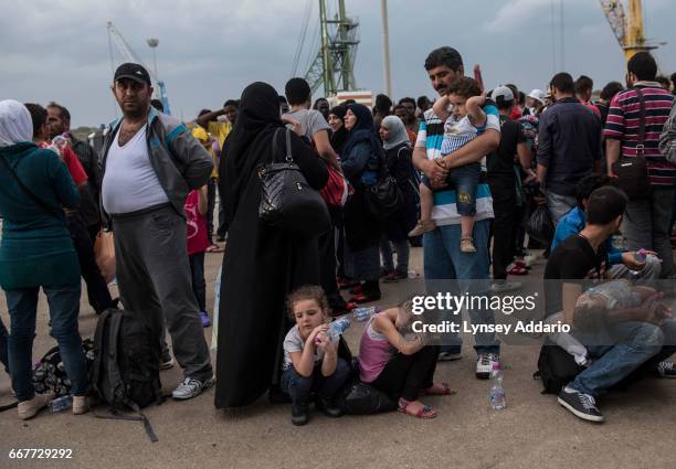 Hundreds of refugees from Syria, Gambia, Eritrea, and Iraq, among other countries, disembark from an Italian navy ship after being intercepted and...