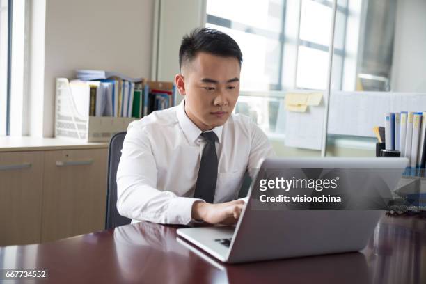 junger geschäftsmann arbeiten am laptop im büro - civil servant stock-fotos und bilder