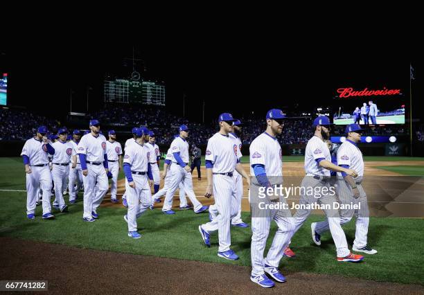 Members of the Chicago Cubs walk back to the dugout after raising the 2016 World series Champions banner before the home opening game against the Los...