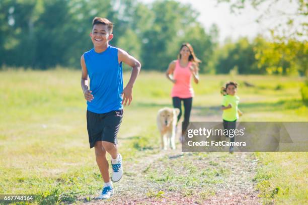 family running following son with dog - family jogging stock pictures, royalty-free photos & images