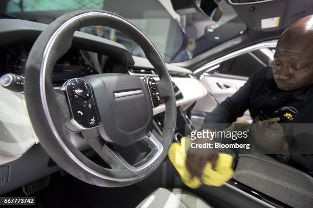 Worker cleans the interior of a Jaguar Land Rover Automotive Plc Range Rover Velar HSE sport utility vehicle during the 2017 New York International...