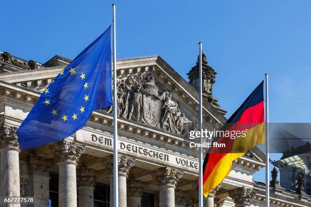 eu- and german flag with the famous inscription on the architrave on the west portal of the reichstag building in berlin: "dem deutschen volke" - democracy stock pictures, royalty-free photos & images