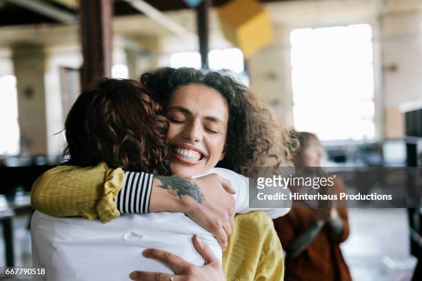 closeup of office workers hugging - sostegno morale foto e immagini stock