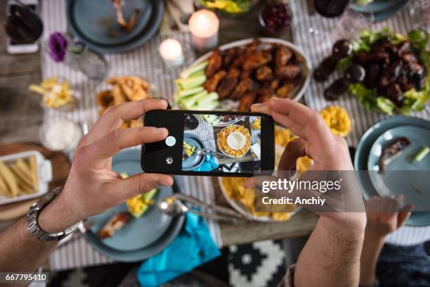 male hipster taking a photo of his dinner - hand chicken wing stock pictures, royalty-free photos & images