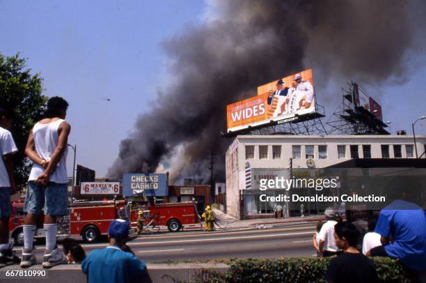People look on as the LA Fire Department attempts to put out a fire at 307 S Vermont Ave in widespread riots that erupted after the acquittal of 4...