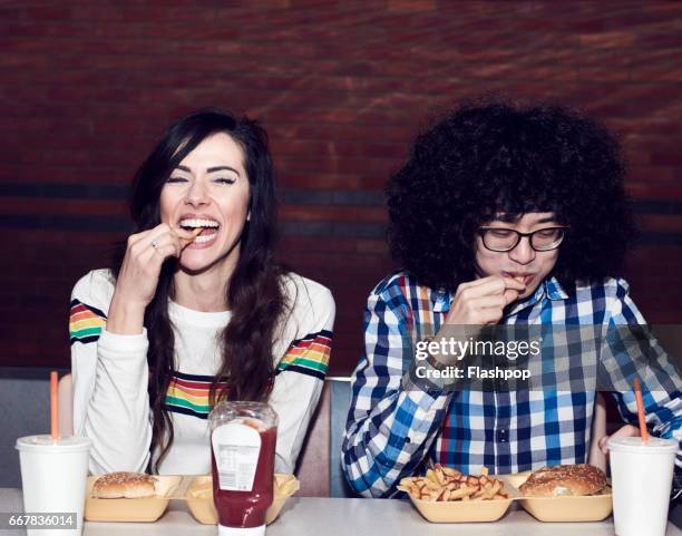 couple eating fast food - women side by side stock pictures, royalty-free photos & images