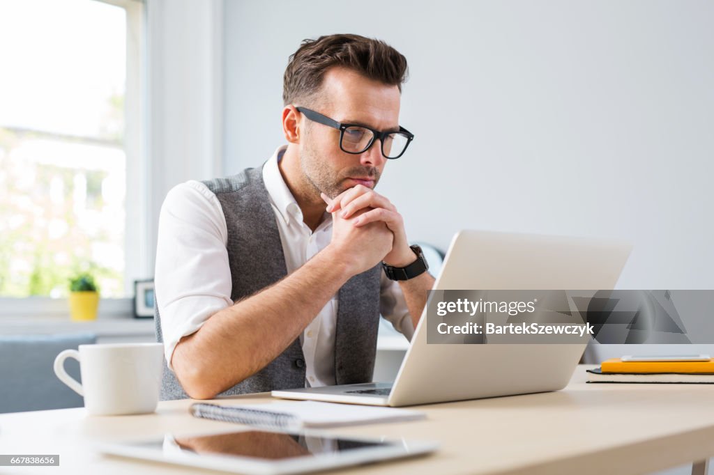 Man in glasses working on laptop from home