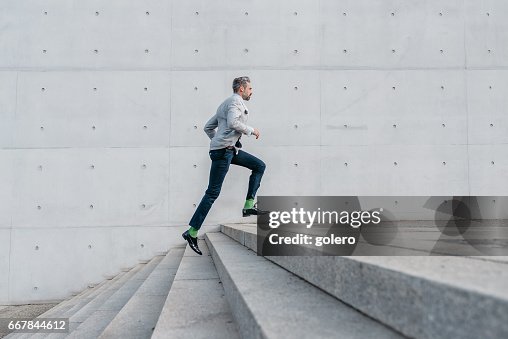 Elegant bearded businessman running up stairs outdoors Elegant bearded businessman running up stairs outdoors