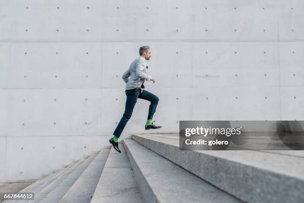 elegant bearded businessman running up stairs outdoors - staircase imagens e fotografias de stock