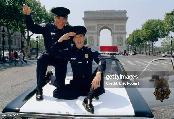 The actors of the movie Police Academy 6 in Paris. G.W. Bailey and Lance Kinsey ride on a police car down the Champs-Elysees.