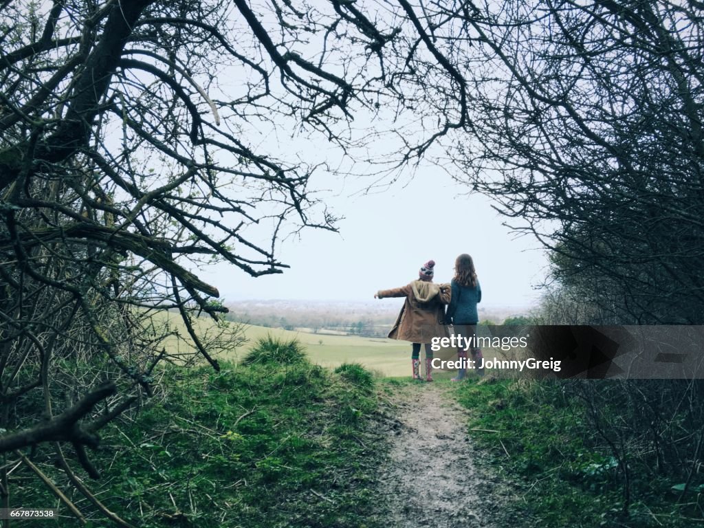 Two young friends on countryside walk pointing way forward