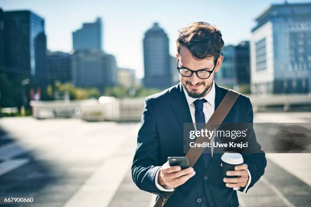 young businessman having coffee while using smart phone - well dressed young man stock pictures, royalty-free photos & images