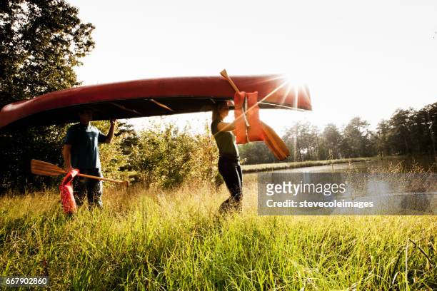 young couple carry a canoe - grass land stock pictures, royalty-free photos & images